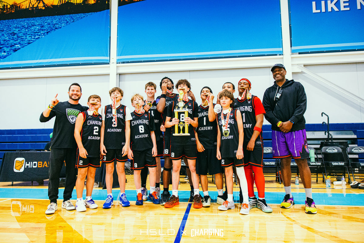 Charg1ng basketball team and coaches celebrating with a trophy and medals.