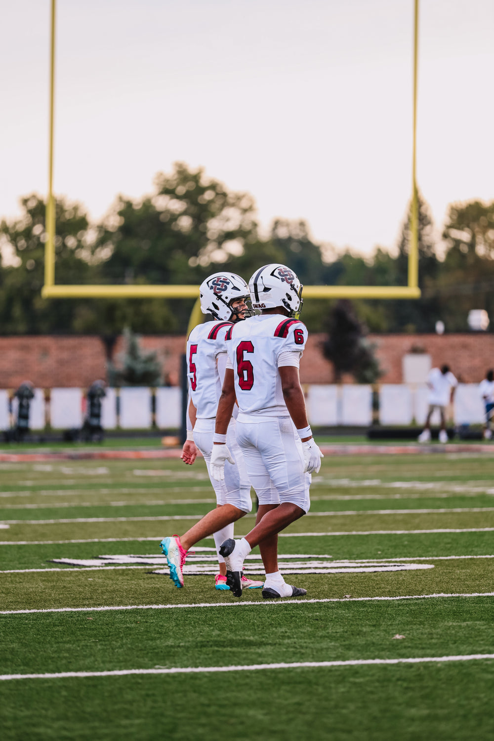 University School football players wearing white jerseys numbered 5 and 6 on the field.