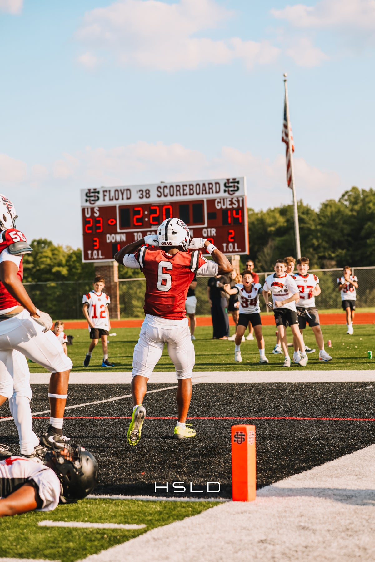 Football player celebrating in the end zone in front of supporters.