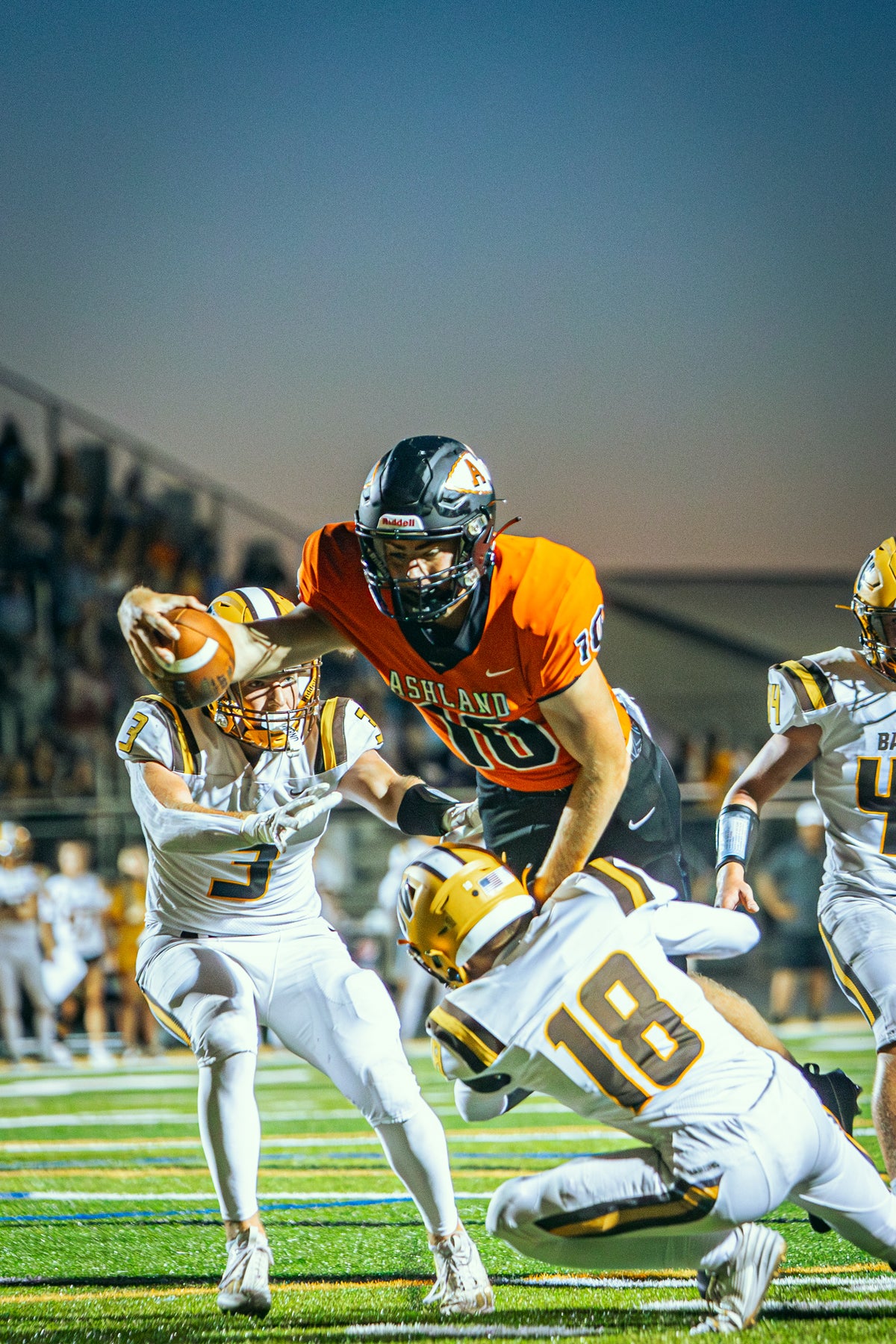 Ashland football player reaching forward with the ball over defenders.