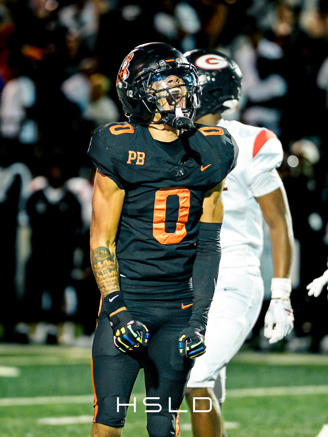 Football player in a black and orange uniform celebrating on the field.
