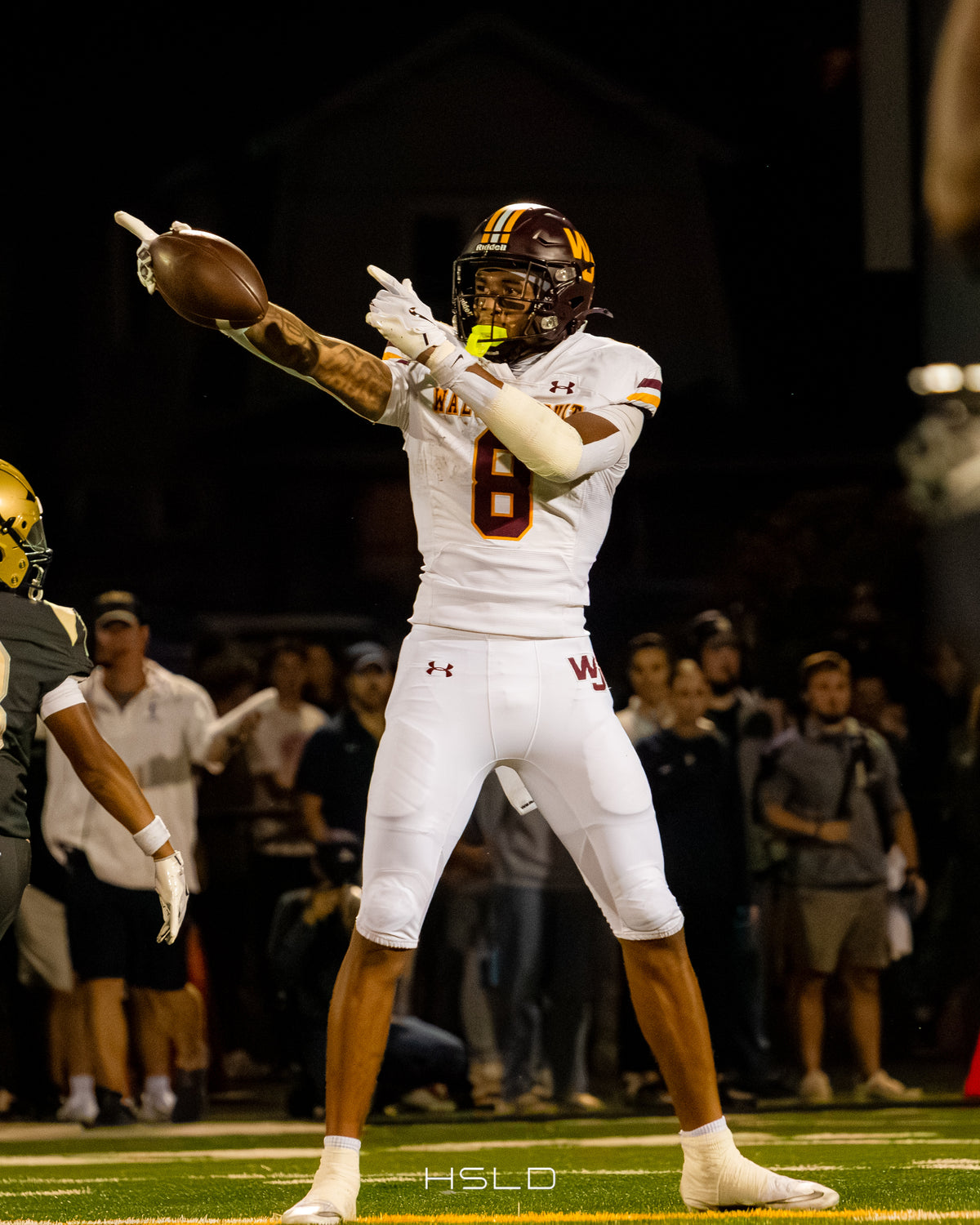 Football player in a white uniform celebrating with the ball.