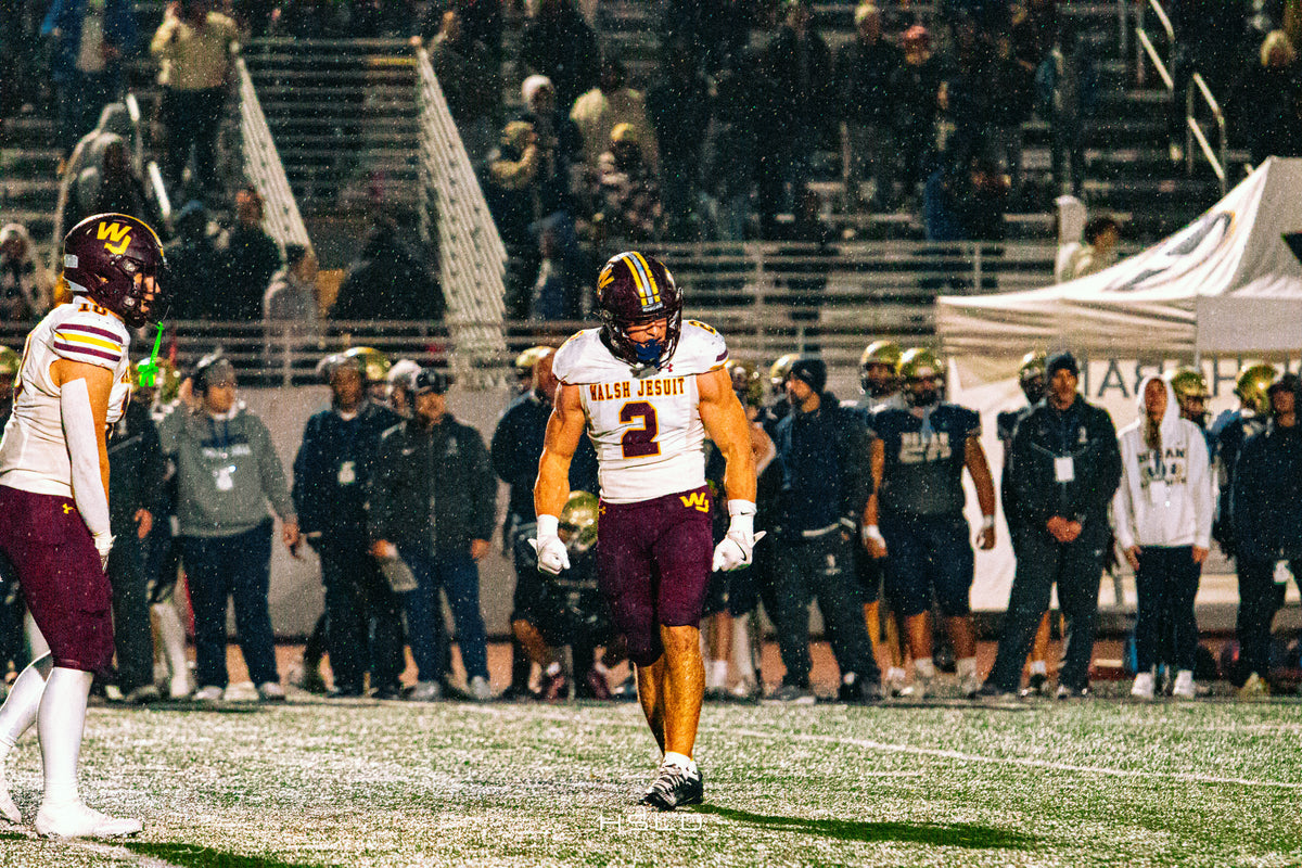 Football player in a white and maroon uniform on a rain-soaked field.