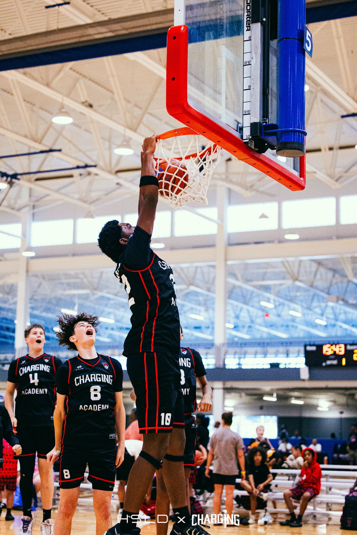 Charg1ng basketball player dunking as teammates look on.